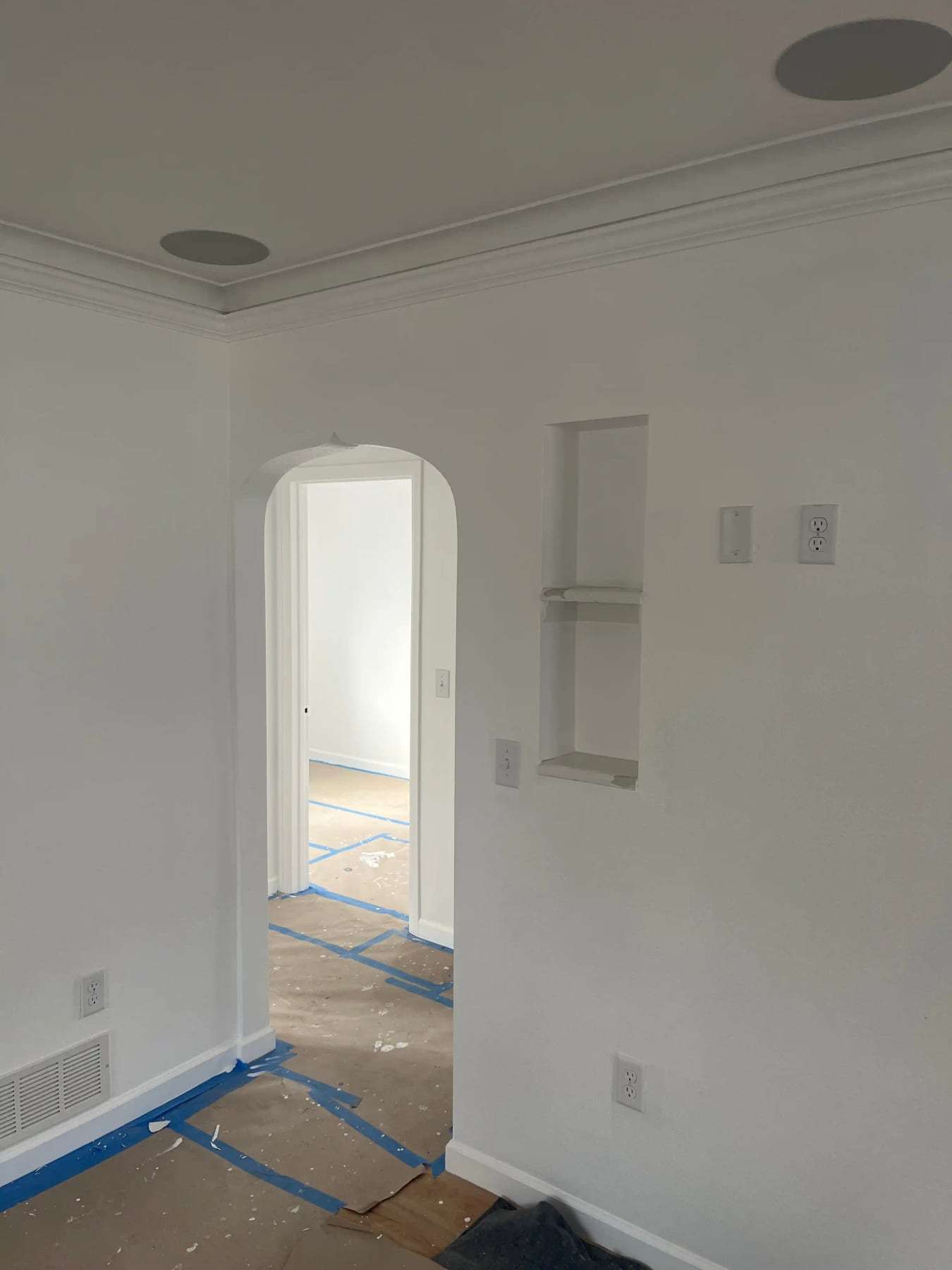 Finished room with an arched doorway and floor protection still down